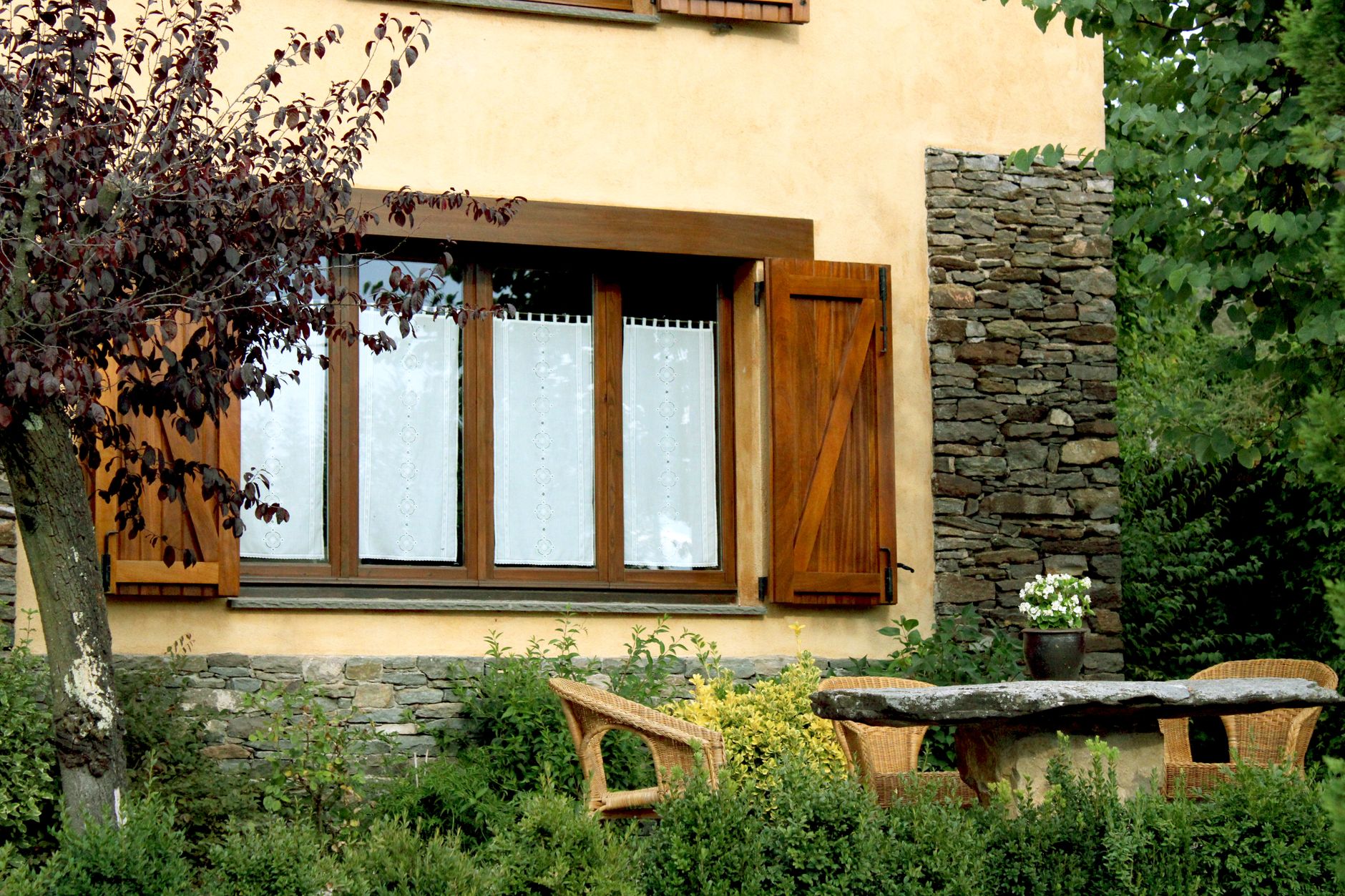Wooden window with shutters and garden table in a rustic Spanish setting.